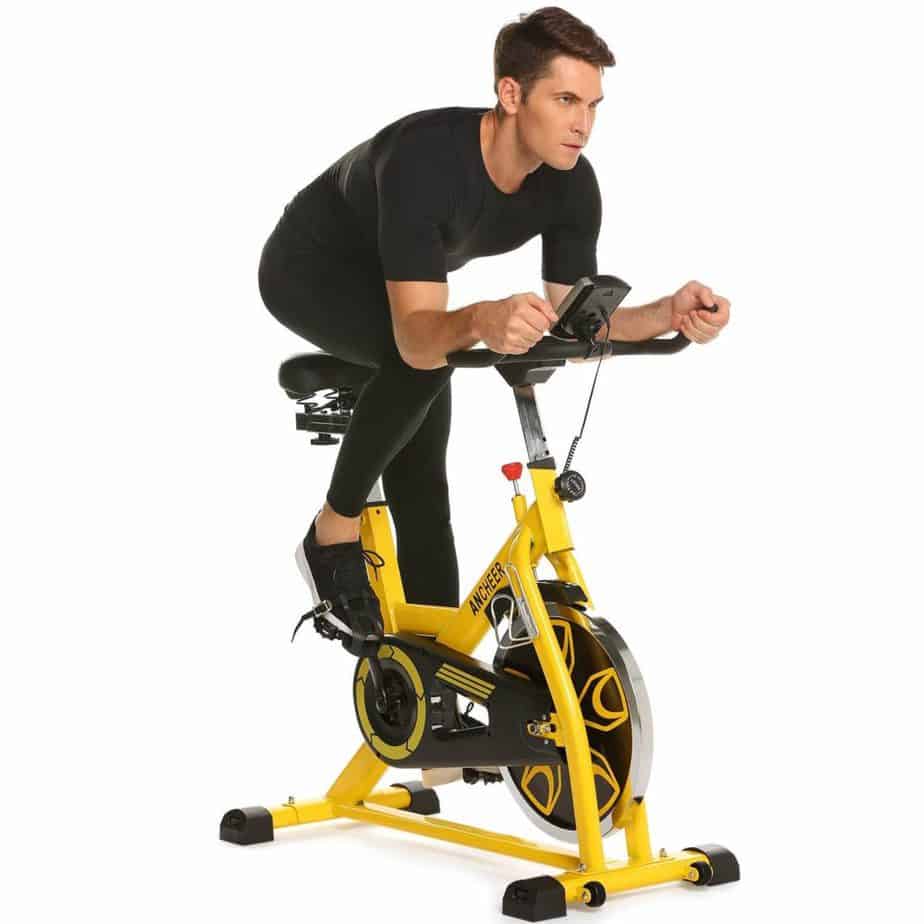 A man is exercisng with the Ancheer Indoor Cycling Bike, Belt Drive B3008