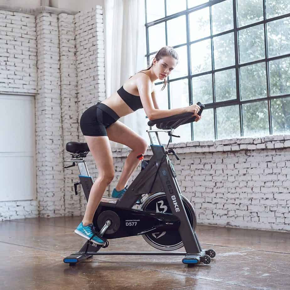A lady is exercising with the L Now Indoor Cycling Bike LD-577