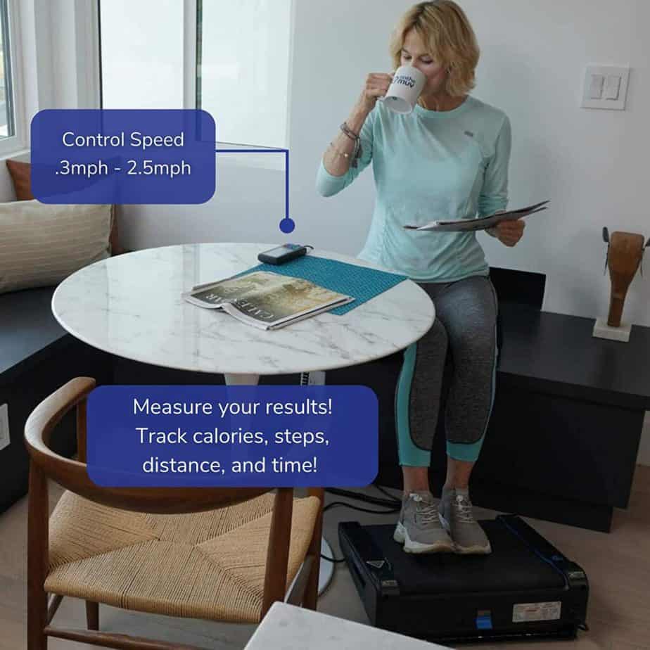 A lady uses the Onthemuv MiniTREAD Compact Electric Treadmill while sitting and enjoying a cup of tea