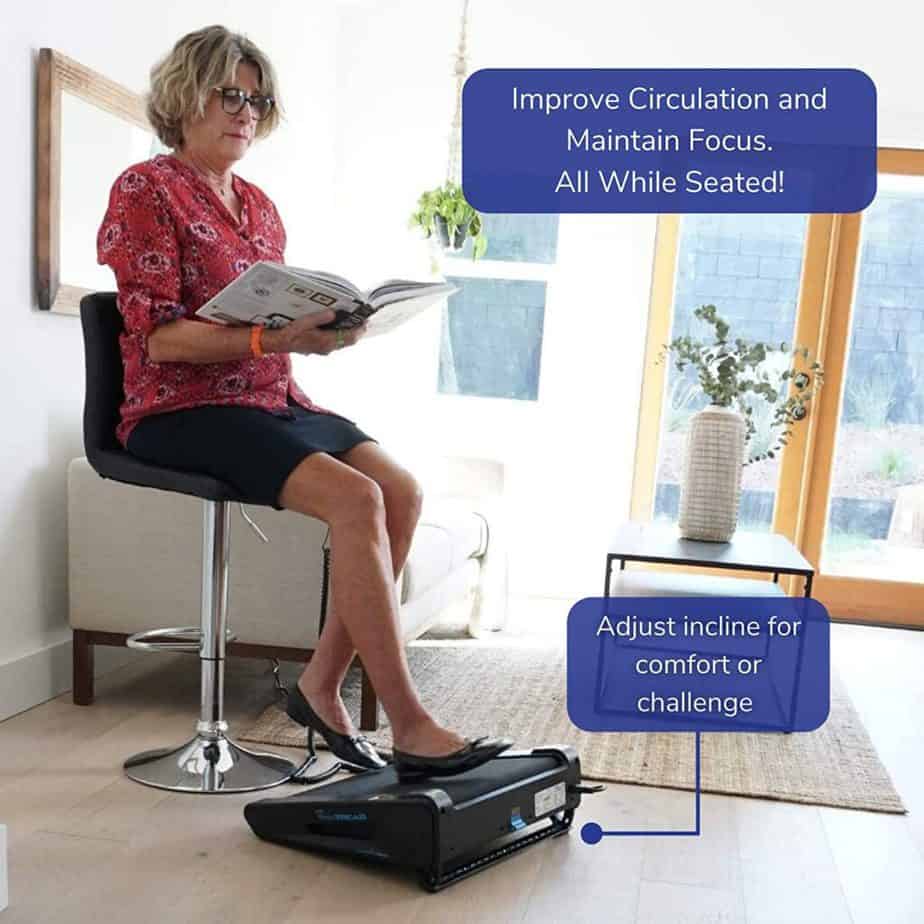 An elderly lady sits and reads a book while using the Onthemuv MiniTREAD Compact Electric Treadmill