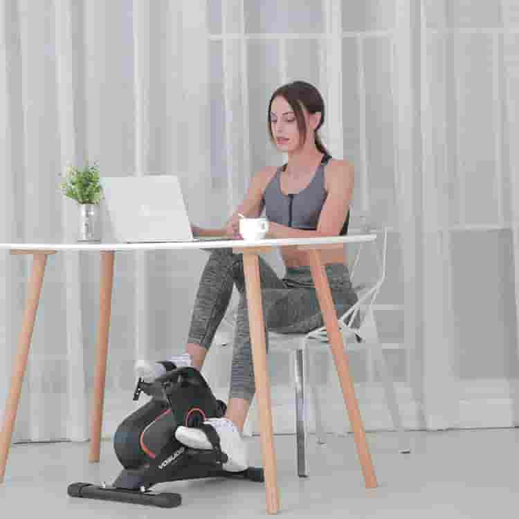 A lady uses the YOSUDA YBM-1 Under Desk Cycling Bike  while working on her computer