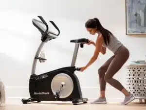 A lady adjusts the seat of the NordicTrack VU 29 Bike