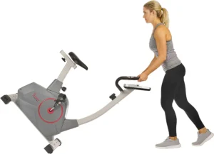 A woman rolls the Sunny Health & Fitness SF-B2952 Upright Bike away to a storage area