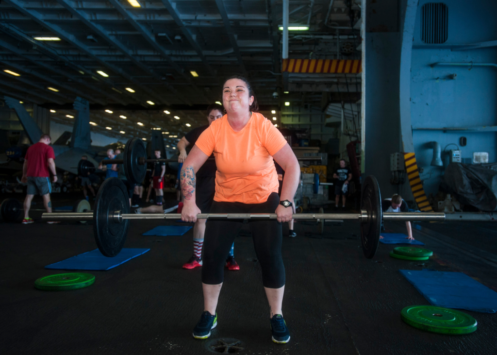 A boy does the hang snatch exercise with a barbell
